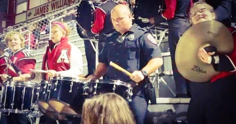 officer playing drums at football game