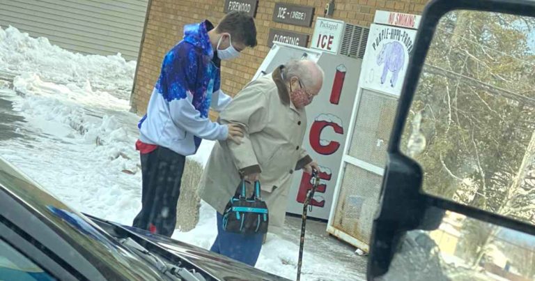 man-helps-elderly-woman-walk-across-ice