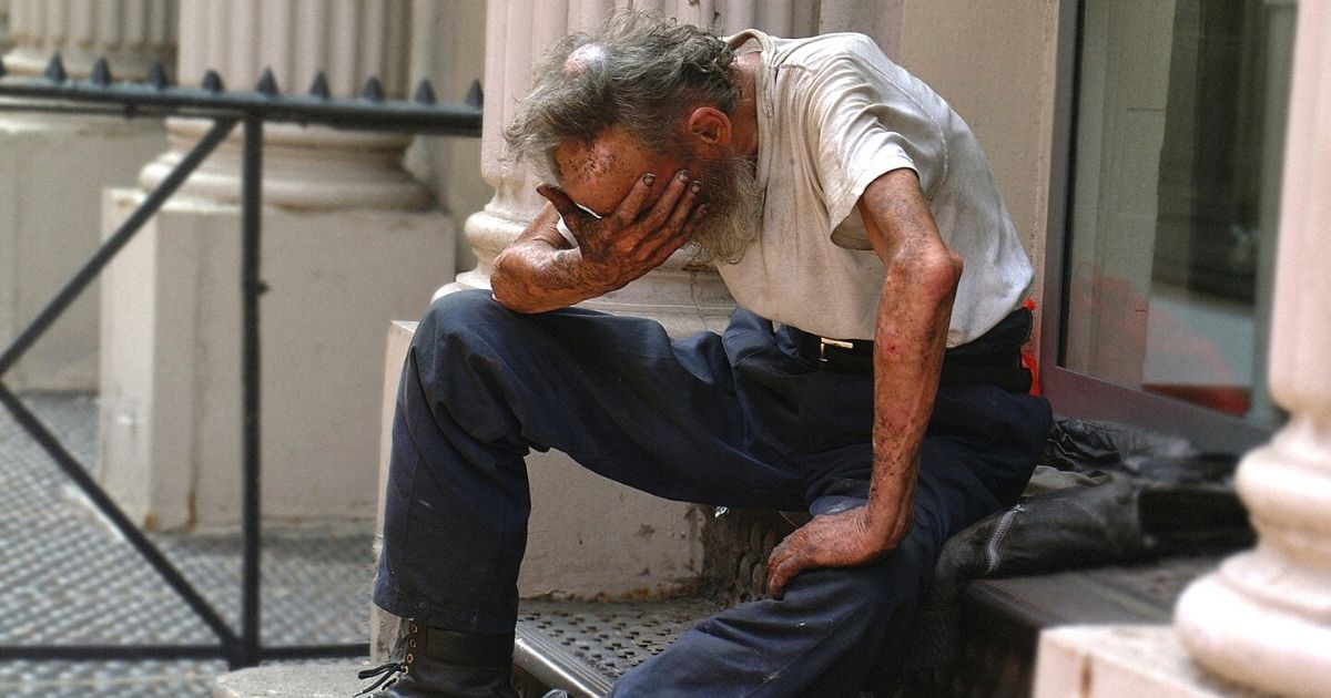 woman gives homeless man water