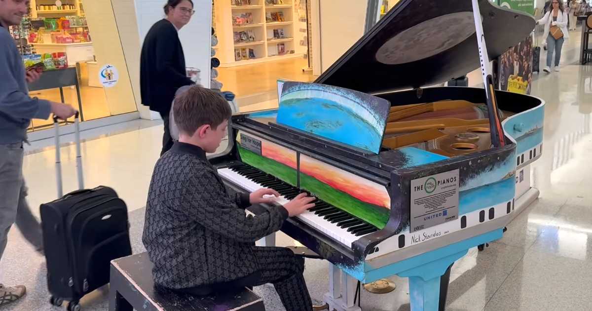 young boy plays airport piano